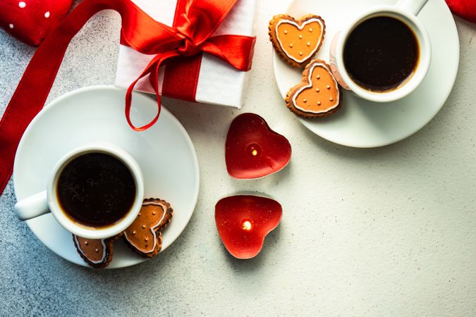 Top view of two coffees with iced cookies and heart candles