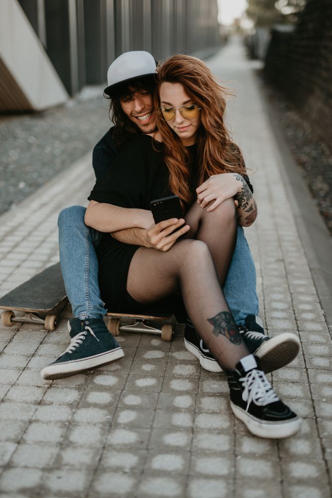 Skaters sitting on road on smartphone