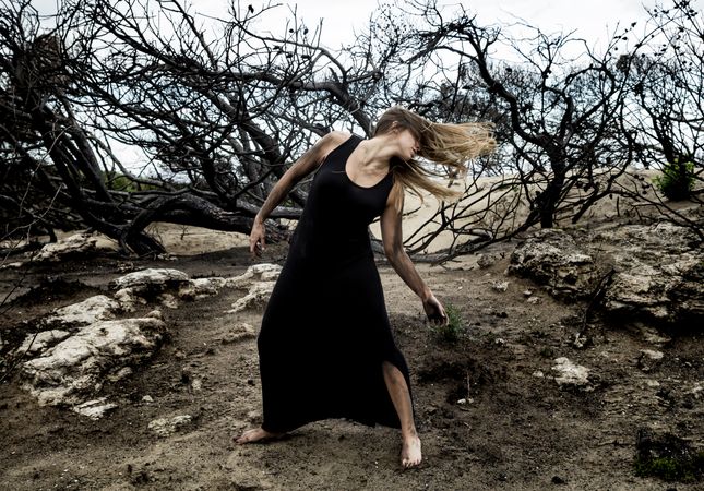 Woman posing on ground near dry trees