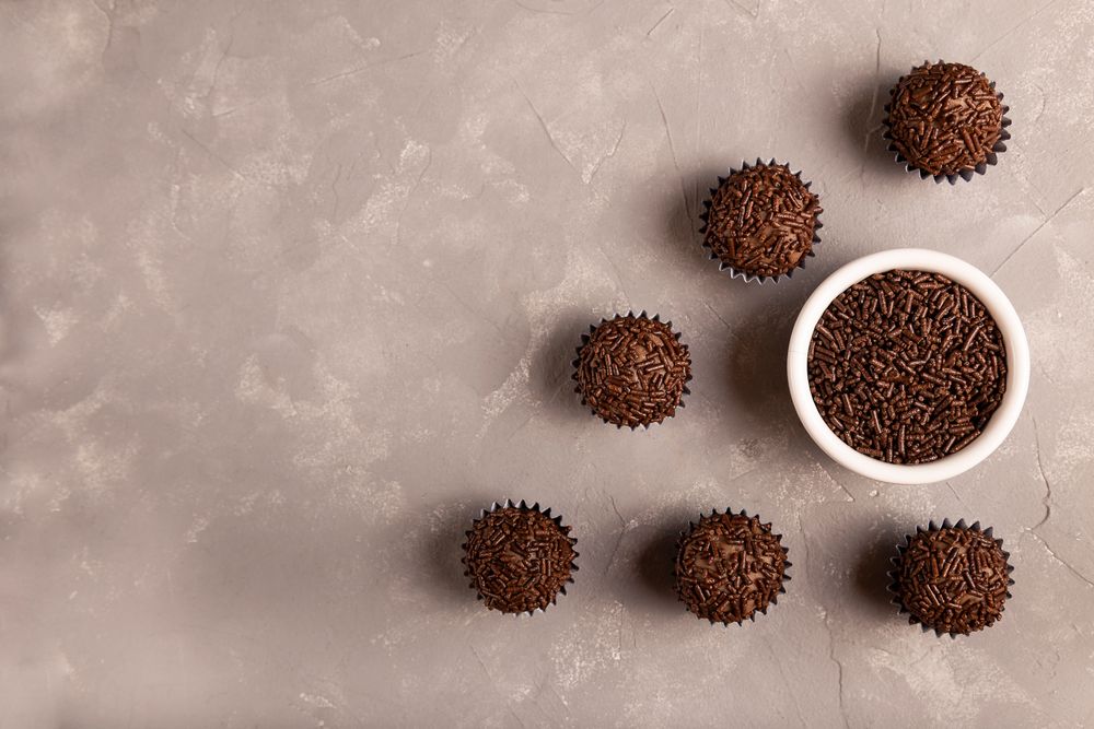 Top view of chocolate truffles with sprinkles on marble surface with space for text