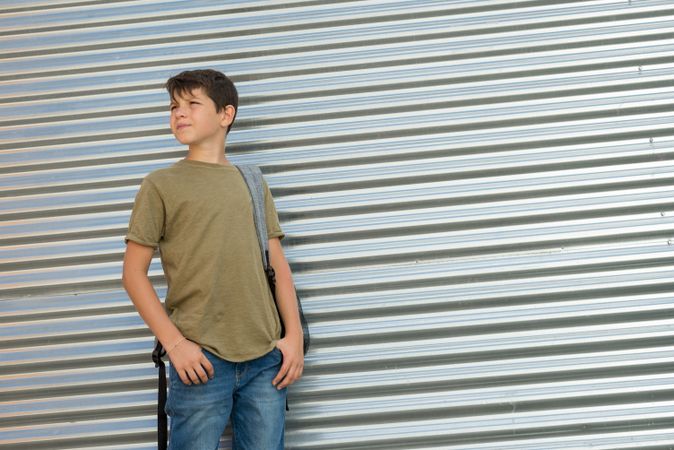 Teenage male in back pack standing outside of street shutter