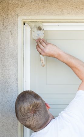 Professional Painter Cutting In With Brush to Paint Garage Door Frame