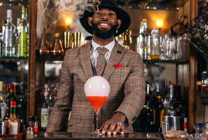 Stylish Black bartender preparing a cocktail with a smoke bubble in a traditional cocktail bar