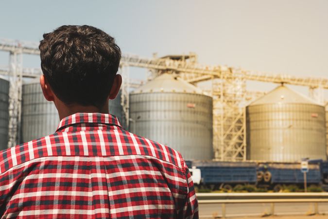 Young man against grain silos. Agriculture business