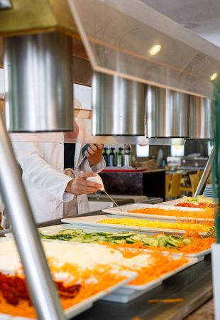 Adult employee checking food quality in canteen