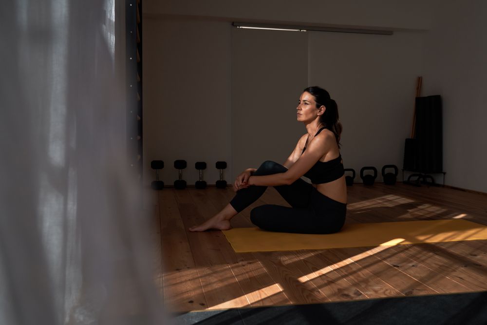 Woman in sportswear embracing knee in gym