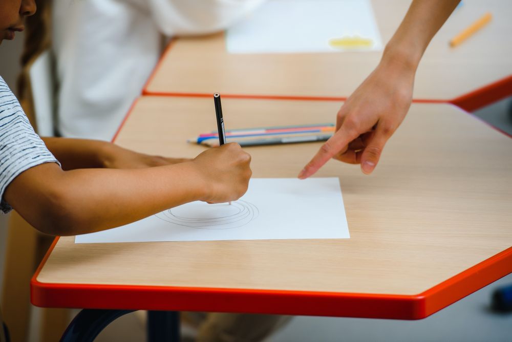 Cropped image of teacher's hand guiding a student
