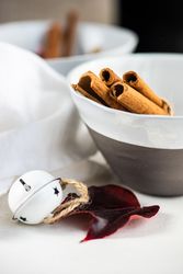 Winter table setting of cinnamon sticks in bowls with bell and leaves