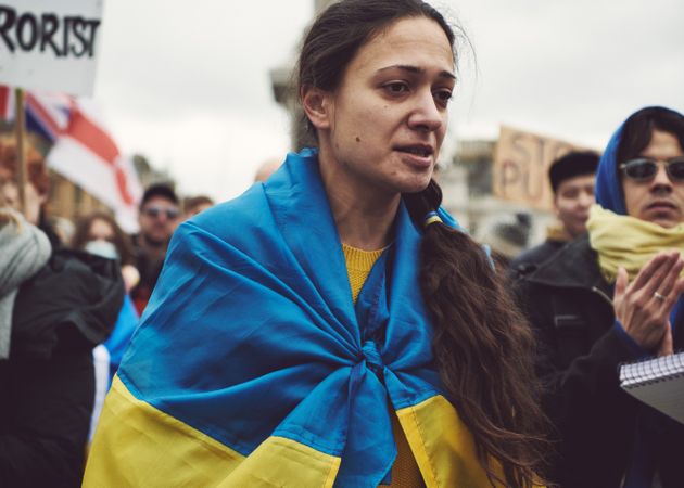 London, England, United Kingdom - March 5 2022: Sad woman draped in Ukrainian flag