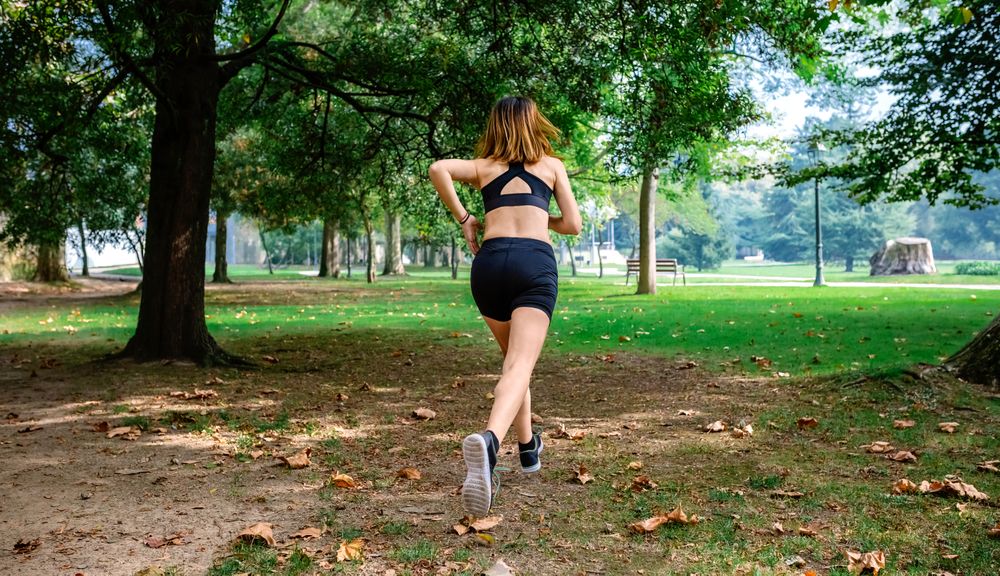 Female athlete running through a park