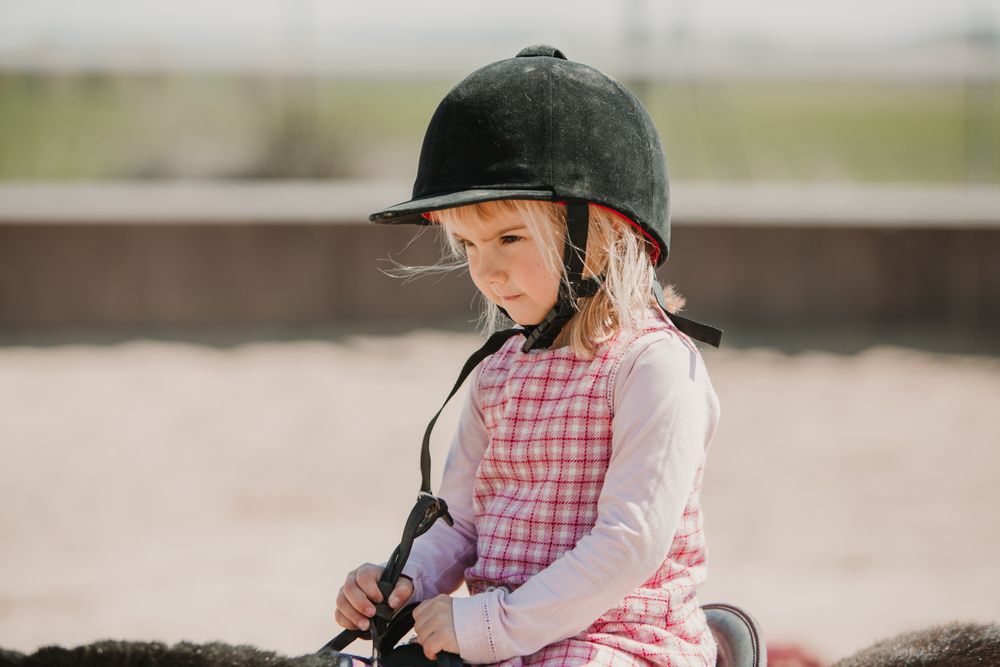 Little girl riding horse on hippodrome