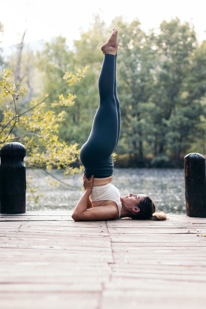 Woman in sportswear doing yoga in nature near a lake