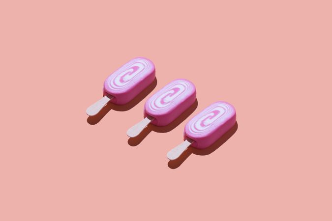 Three pink popsicles on pink background