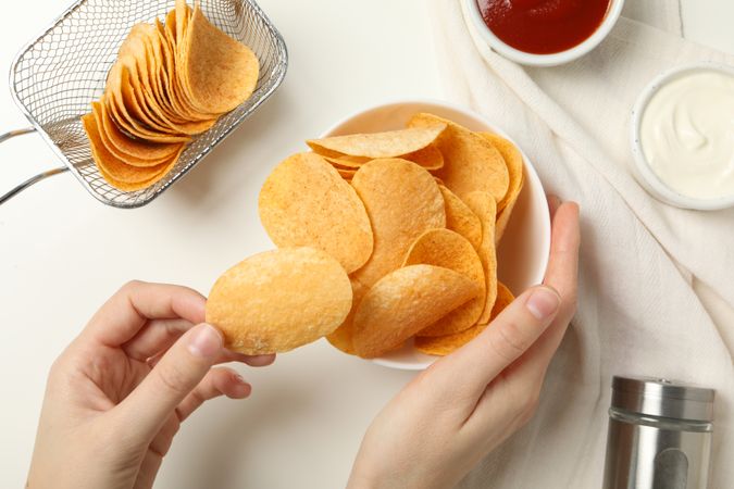 Potato chips in a bowl with sauces on a light background