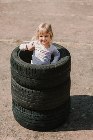 Little girl standing in stack of tires