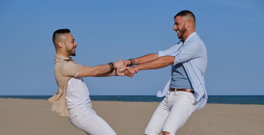 Happy gay couple having fun on beach