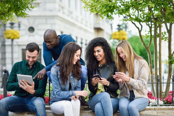Group of women and men smiling and laughing in the street wearing casual clothes