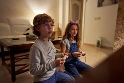 Perplexed children with gaming station sitting at living room