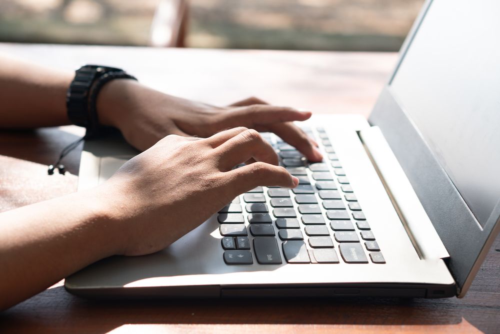 Closeup Asian Young businessman work at outdoor with laptop. Concept of remote and freelance work. Young successful man wearing casual blue cloth.