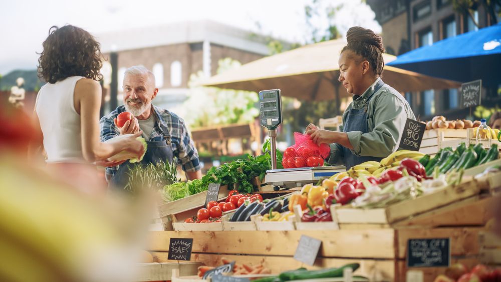 Latina Female Customer Buying Sustainable Organic Tomatoes and Napa Cabbage From a Multiethnic Farmers Couple.