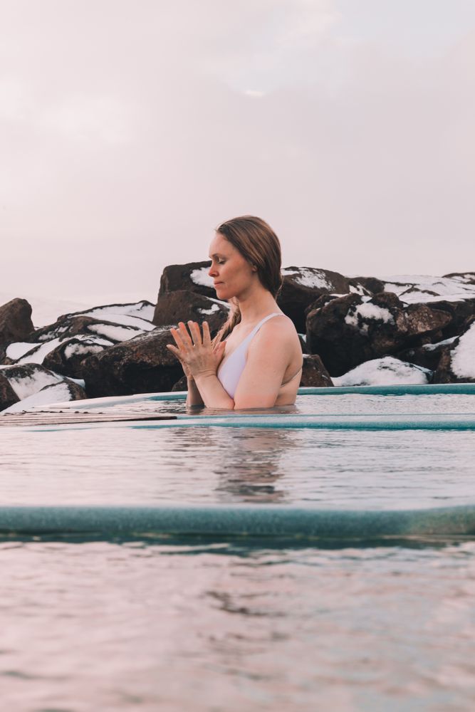 Woman sitting in pool near stones