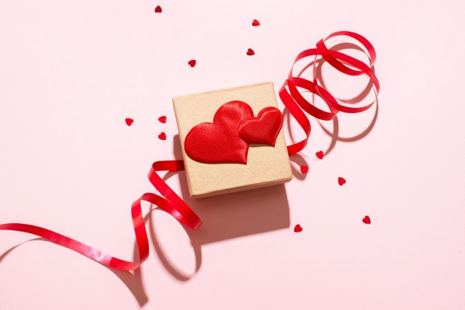 Small gift box with red heart and ribbon on pink background
