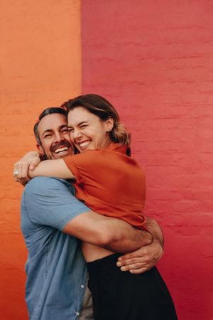 Loving middle aged couple embracing against colored wall