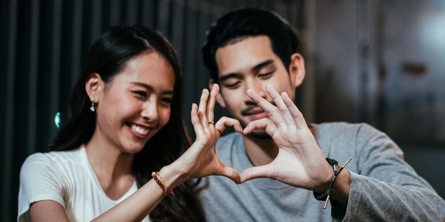Asian couple making heart shape with hands together