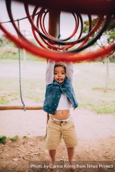 Toddler hanging on a jungle gym at a playground E47M60