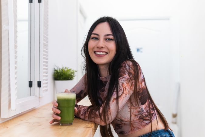 Content woman enjoying green beverage in bar