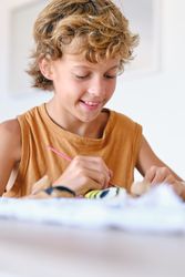 Cute boy painting rock with aquarelle