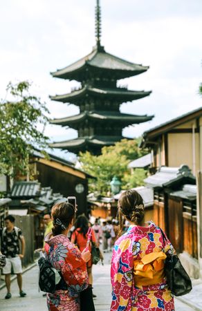 Two women wearing kimonos walking in an alley