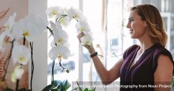 Woman in her flower shop looking at orchids 4BNlW4