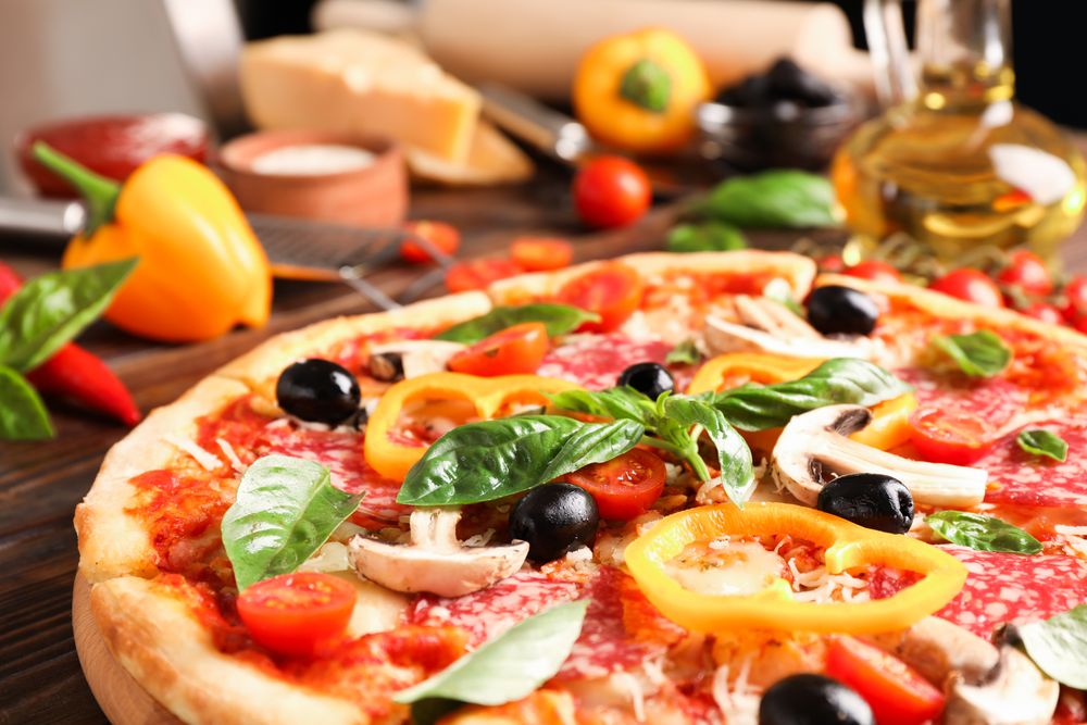Delicious pizza and ingredients on wooden background, close up