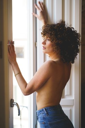 Young woman in topless standing near window