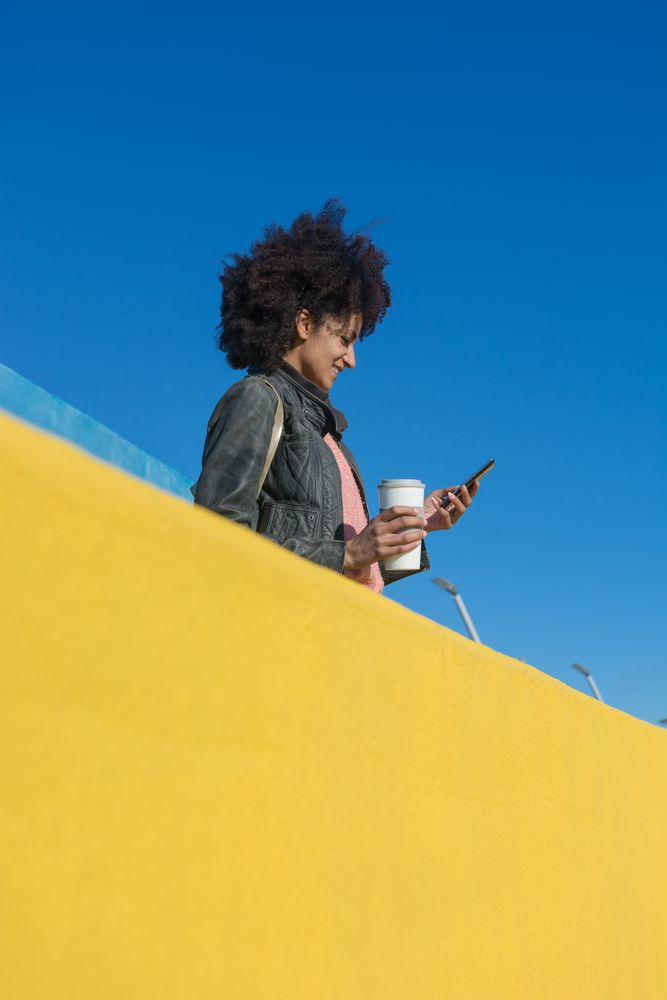 Black woman with afro hair leaning against brightly colored wall