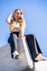 Woman sitting on corner of building roof listening to music
