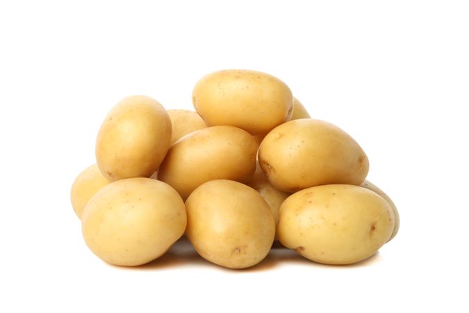 Side view of pile of whole potatoes in blank room