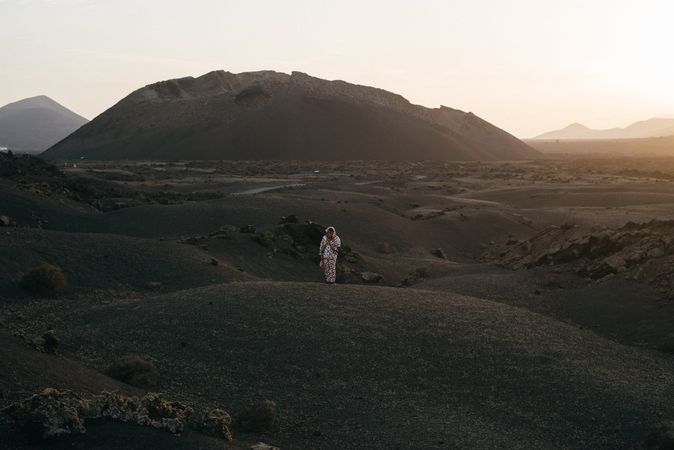 Person in brightly patterned clothes standing on volcanic hills in Lanzarote at dusk