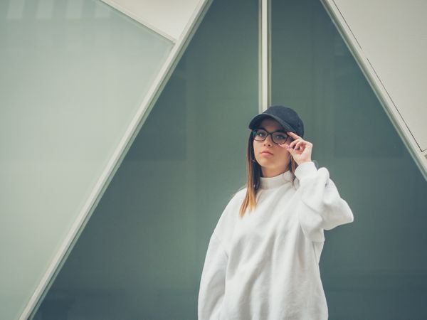 Young woman with glasses standing against wall