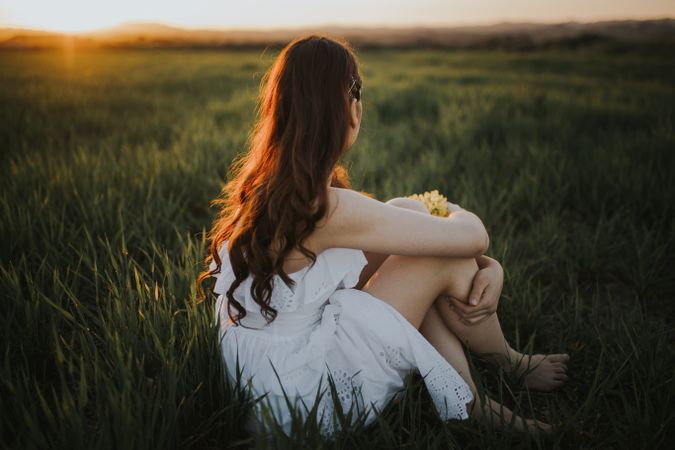 Barefoot woman with flowers in meadow
