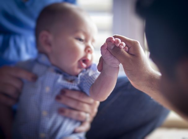 Cute Infant Boy Holds Father's Thumb