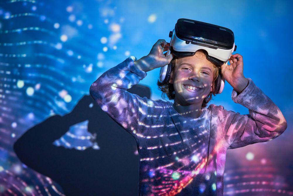 Cheerful child taking off VR headset and smiling at camera