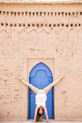 Woman in handstand against old stone wall