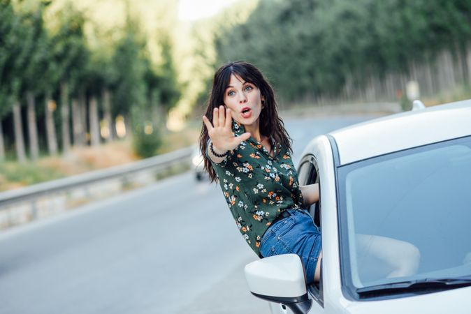 Brunette female hanging outside passenger window with hand out