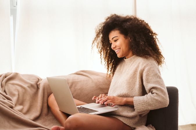 Black female using laptop on sofa