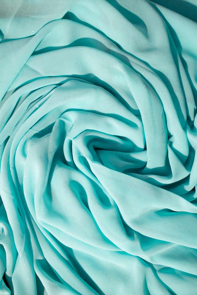 Spiral Twisted Turquoise wavy crumpled fabric with little sparkling dust, texture and  background.