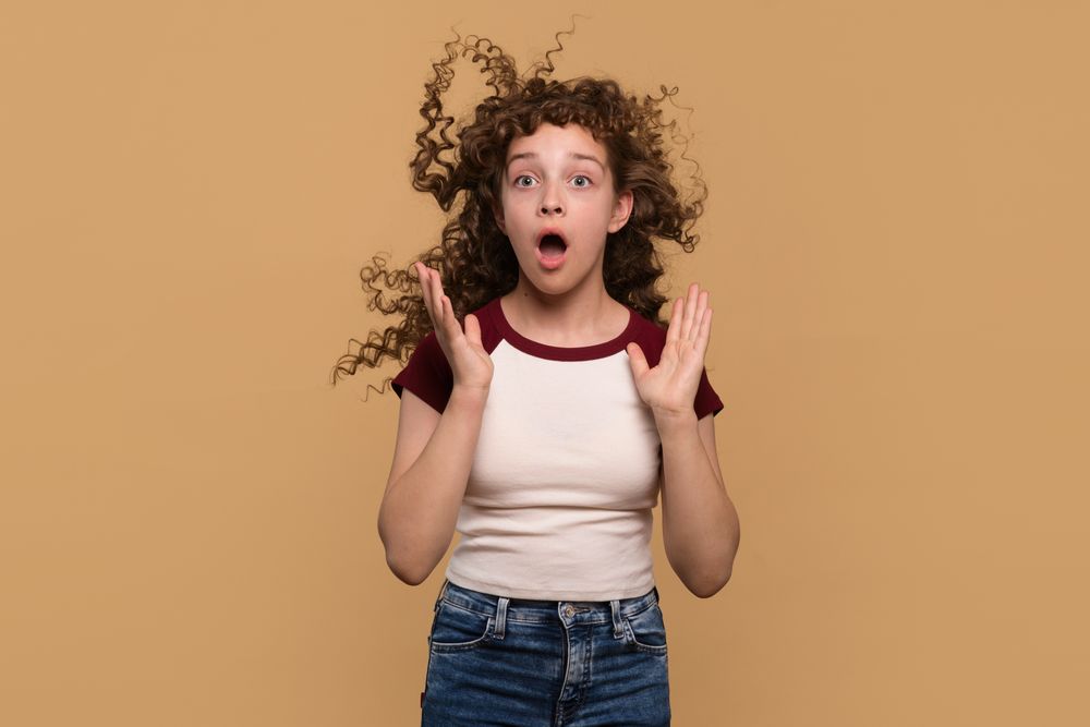 Young girl with hair blowing upwards, expressing surprise