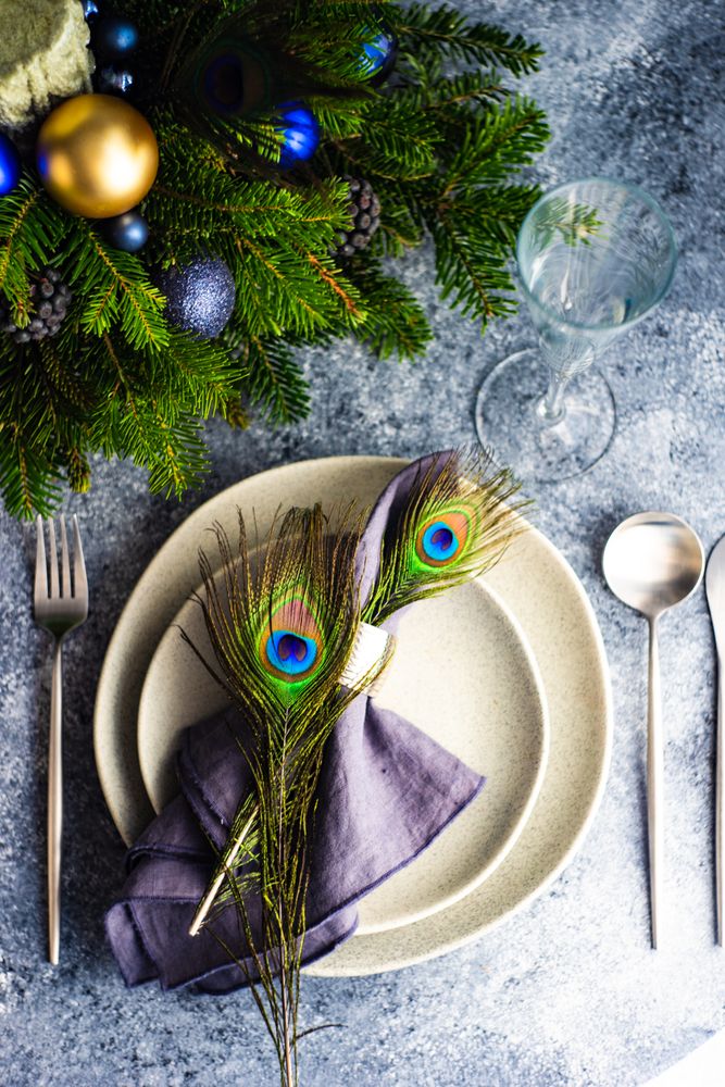 Top view of festive table setting for Christmas dinner with peacock feathers