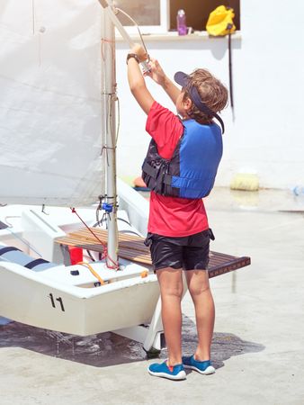Boy preparing yacht for sailing on sunny day